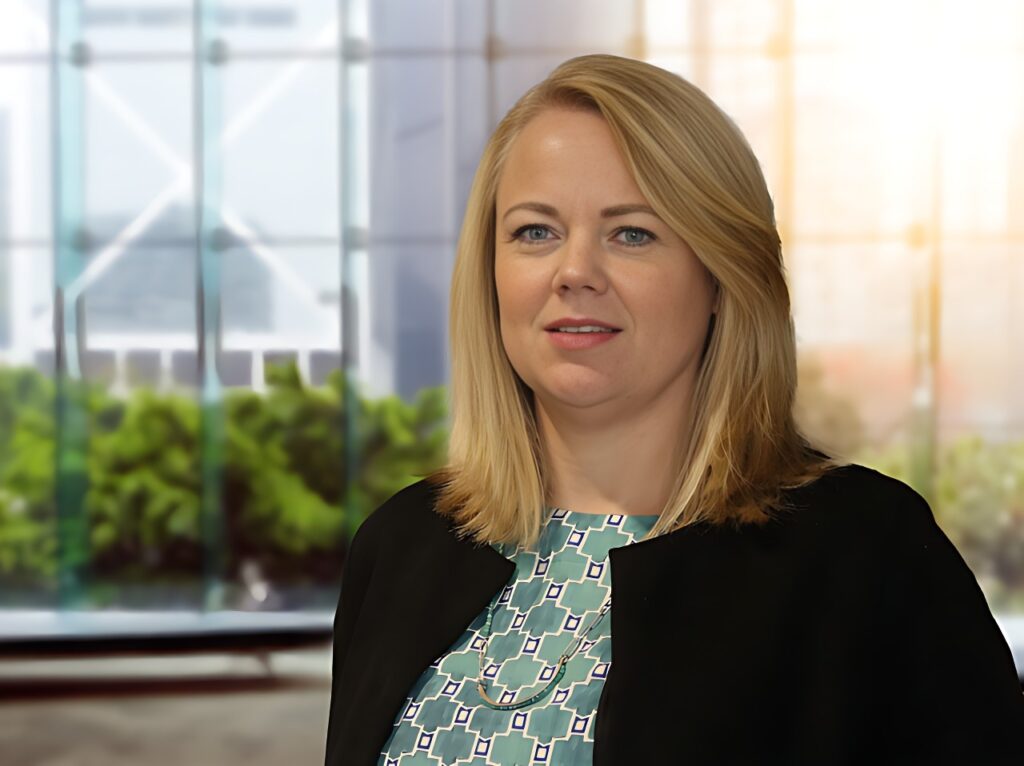 Stephanie Quarmby - The Brief | Namibia's Leading Business & Financial News Professional woman with blonde hair wearing a teal patterned blouse and black blazer, standing in a glass-walled office background.