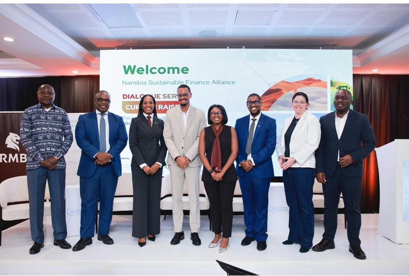 WhatsApp Image 2026-04-21 at 110949 AM - The Brief | Namibia's Leading Business & Financial News Eight professionals in business attire stand on a stage in front of a screen that reads 'Welcome Namibia Sustainable Finance Alliance'.