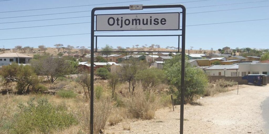 OTJOMUISE - The Brief | Namibia's Leading Business & Financial News Town entrance sign reading 'Otjomuse' over a dusty, dry landscape with small houses in the background.