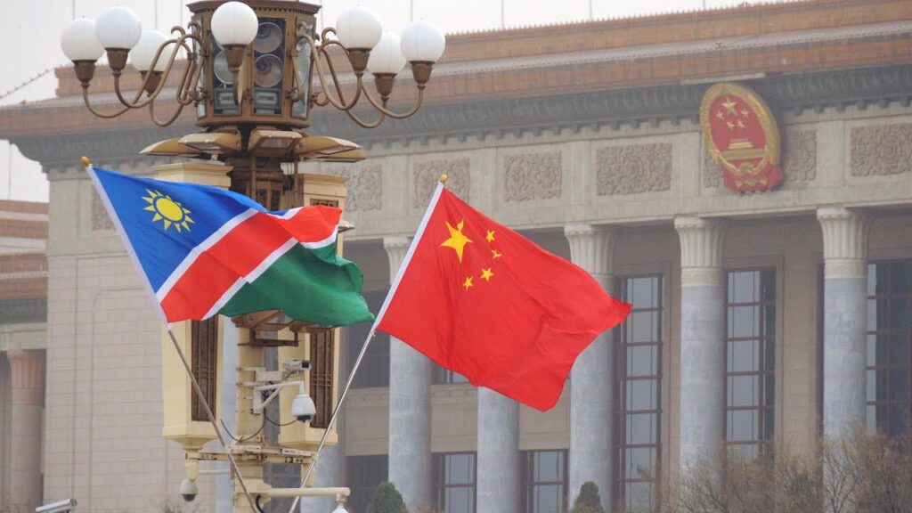 Namibia and China flags waving in front of a government building with decorative columns.
