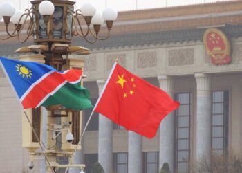 Namibia and China flags waving in front of a government building with decorative columns.