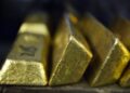 GOLD3 - The Brief | Namibia's Leading Business & Financial News Gold ingots stacked in a row, with reflective, yellow-gold surfaces catching light on a dark background.