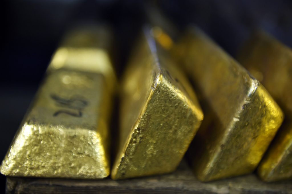GOLD3 - The Brief | Namibia's Leading Business & Financial News Gold ingots stacked in a row, with reflective, yellow-gold surfaces catching light on a dark background.