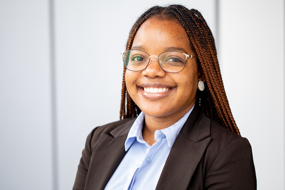 Leena Franscisco1 - The Brief | Namibia's Leading Business & Financial News Professional headshot of a smiling Black woman with braided hair, wearing glasses, a light blue shirt and black blazer in an office setting.