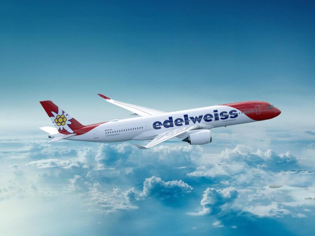 EDELWIESS - The Brief | Namibia's Leading Business & Financial News White and red Edelweiss airliner in flight above fluffy clouds, blue sky background, logo on the fuselage.