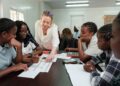 LEARNERS - The Brief | Namibia's Leading Business & Financial News Teacher leaning over a table to help diverse students with worksheets in a bright classroom.