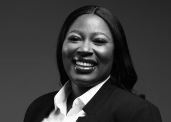 Smiling Black woman in a white collared shirt and dark blazer, looking at the camera.