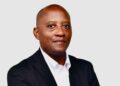ERASTUS NASHIMA - The Brief | Namibia's Leading Business & Financial News Professional headshot of a man in a black suit and white shirt against a light gray background, facing the camera.