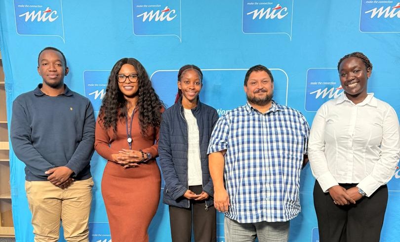 WhatsApp Image 2026-05-11 at 115508 AM - The Brief | Namibia's Leading Business & Financial News Group of five diverse individuals posing for a photo in front of a blue backdrop with the MTC logo at an event.