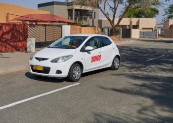 White sedan with 'YANGO' branding parked on a residential street, front wheel turned slightly left.
