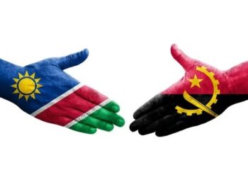 Two hands painted with the Namibia and Angola flags reach toward each other for a handshake, symbolizing cooperation between the two countries.
