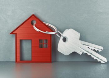 Red house-shaped keychain with a ring of two silver keys, symbolizing home ownership.