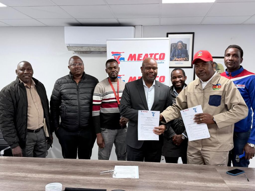 WhatsApp Image 2026-05-19 at 25846 PM - The Brief | Namibia's Leading Business & Financial News Group of men in an office posing with signed documents in front of a MEATCO banner and framed photos, indicating a formal agreement ceremony.
