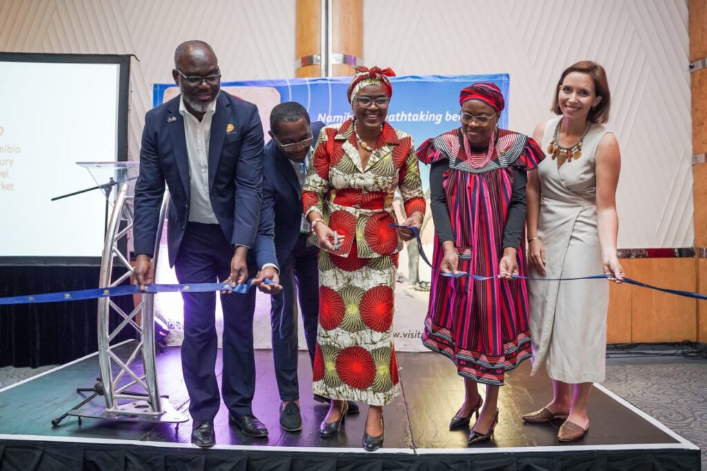 WhatsApp Image 2026-05-20 at 114241 AM - The Brief | Namibia's Leading Business & Financial News Five people in formal and traditional dress cut a blue ribbon on a stage during a ceremony, smiling at the audience.