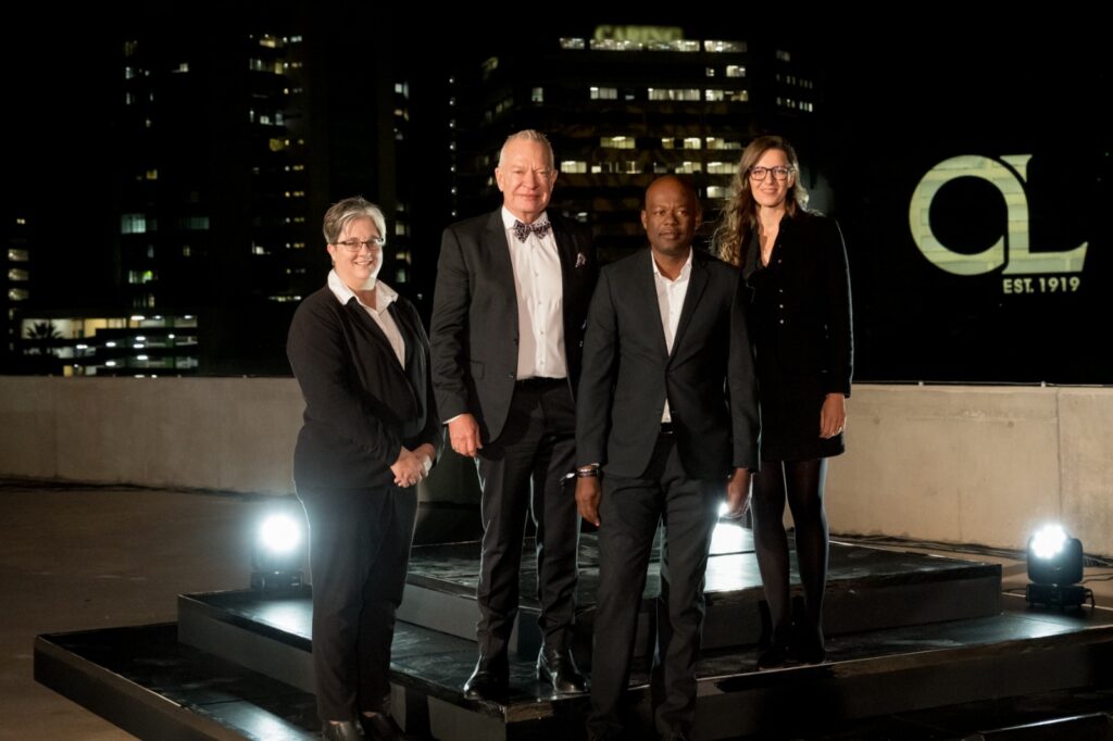 WhatsApp Image 2026-05-21 at 73528 AM - The Brief | Namibia's Leading Business & Financial News Four professionals in formal attire pose on a rooftop stage at night with city lights behind them.