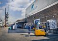 Port loading dock at Ocean Group with forklifts, workers in safety gear, and stacked pallets for shipment by sea transport