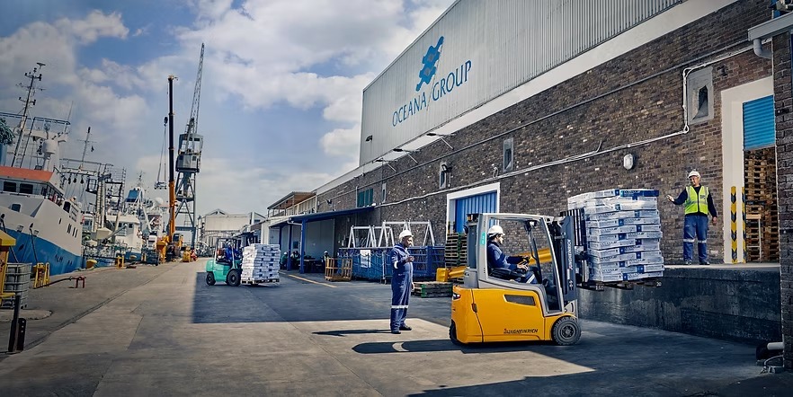 oceana group - The Brief | Namibia's Leading Business & Financial News Port loading dock at Ocean Group with forklifts, workers in safety gear, and stacked pallets for shipment by sea transport