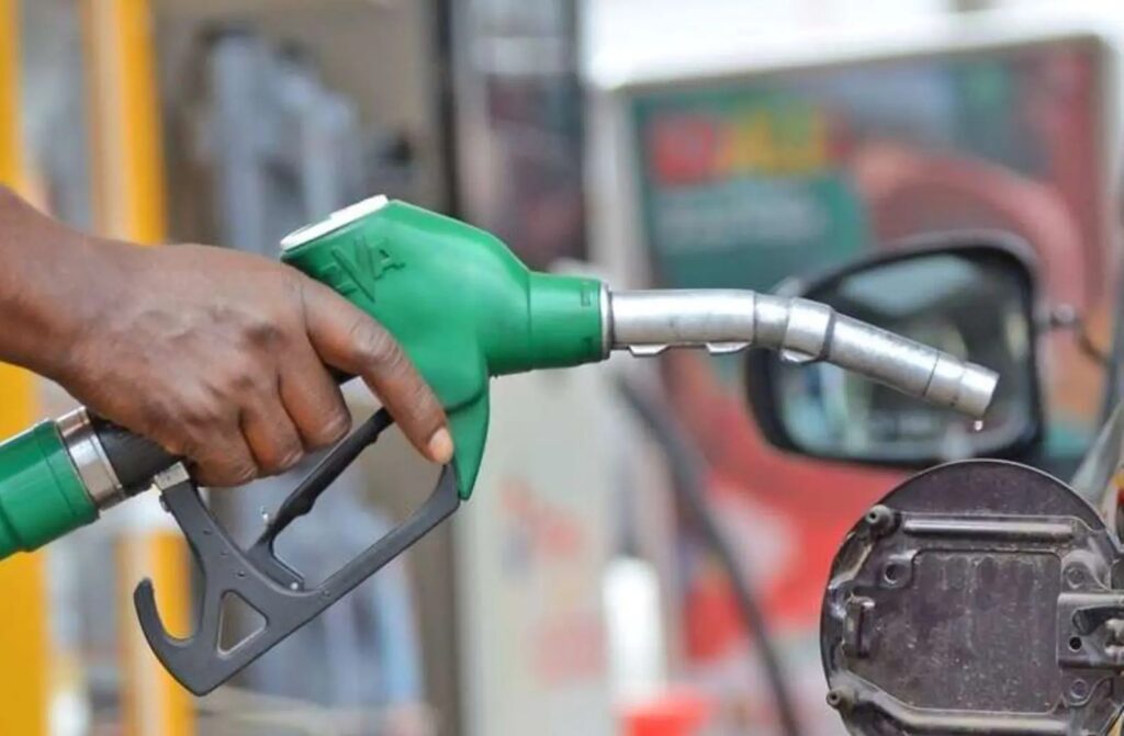 Close-up of a person fueling a car with a green gas pump nozzle at the fuel cap.