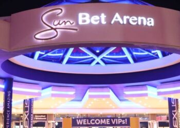 Exterior view of the Sun Bet Arena entrance with purple neon lights and a circular overhang, giving a vibrant, glowing look at night.