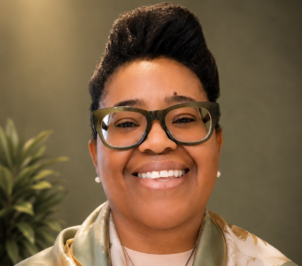Suzana Ingrid Malunga - The Brief | Namibia's Leading Business & Financial News Close-up portrait of a smiling woman with large rectangular glasses, wearing a patterned scarf.