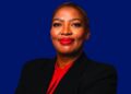 Olebile Makhupe - The Brief | Namibia's Leading Business & Financial News Professional headshot of a confident woman wearing a black blazer and red blouse against a blue background