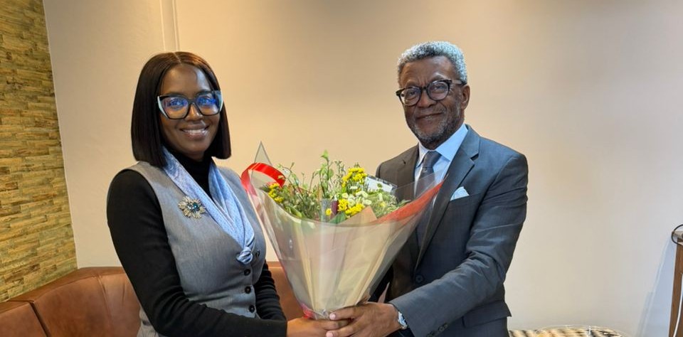 WhatsApp Image 2026-06-04 at 53104 PM - The Brief | Namibia's Leading Business & Financial News Two professionally dressed individuals exchange a bouquet of flowers in a bright, modern room.