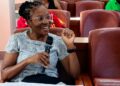 Paulina Shipahu - The Brief | Namibia's Leading Business & Financial News Smiling woman with glasses sits in a conference room, holding a microphone and speaking.