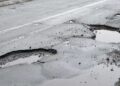 Windhoek potholes - The Brief | Namibia's Leading Business & Financial News Pockmarked road with large potholes filled with water and loose gravel along the edge of a street.