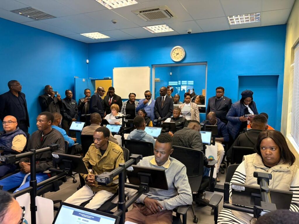 WhatsApp Image 2026-06-08 at 115257 AM - The Brief | Namibia's Leading Business & Financial News Adults in a computer lab seated at workstations while a group stands at the back of a blue-walled room.