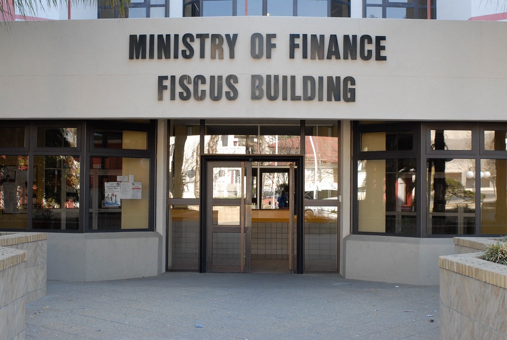 Finance Ministry - The Brief | Namibia's Leading Business & Financial News Front entrance of the Ministry of Finance, with a large sign reading'MINISTRY OF FINANCE FISCUS BUILDING' above glass doors.