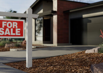 Red and white 'For Sale' sign on a white post in front of a modern house with a concrete driveway.