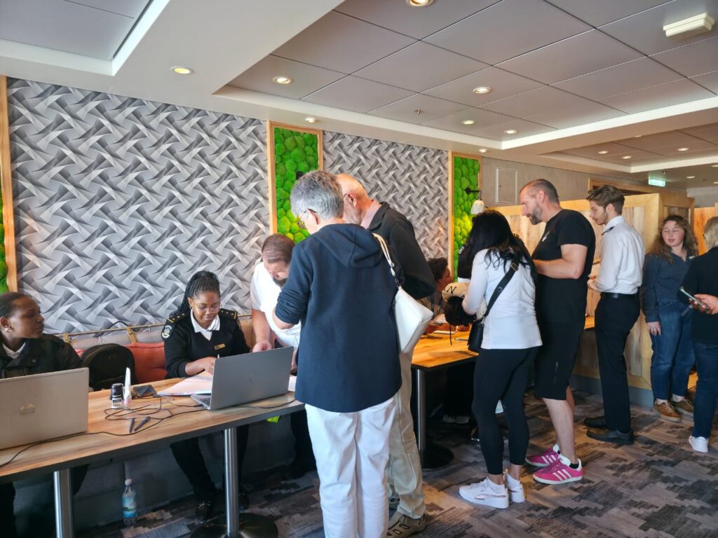 Registration desk in a conference lobby with staff helping attendees and people queuing for check-in.