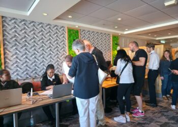 Registration desk in a conference lobby with staff helping attendees and people queuing for check-in.