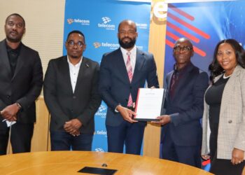 Five professionals pose at a telecom event; center man in navy suit holds a framed certificate.