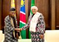 WhatsApp Image 2026-06-10 at 110516 AM - The Brief | Namibia's Leading Business & Financial News Two formally dressed officials shake hands in front of national flags in a wooden-paneled room.