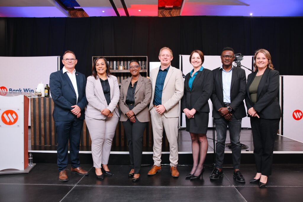 WhatsApp Image 2026-06-10 at 122336 PM - The Brief | Namibia's Leading Business & Financial News Group of seven professionals in business attire posing on a stage for a photo at a corporate event, smiling at the camera.