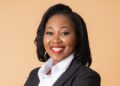 LISA MATOMOLA - The Brief | Namibia's Leading Business & Financial News Portrait of a smiling professional woman in a black blazer and white shirt against a beige background.