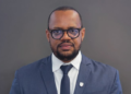 Ernest Hamukwaya - The Brief | Namibia's Leading Business & Financial News Head-and-shoulders portrait of a man in a navy suit and glasses, looking at the camera, with a gray background.