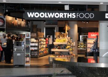 Woolworths Food storefront interior with a central fruit and bread display and shoppers inside.
