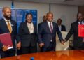 WhatsApp Image 2026-06-12 at 111820 AM - The Brief | Namibia's Leading Business & Financial News Group of five professionals in suits holding hands across a conference table during a signing ceremony at a telecom event