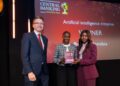 WhatsApp Image 2026-06-12 at 125921 PM - The Brief | Namibia's Leading Business & Financial News Three people on stage at Central Banking Awards 2026; the winner holds a plaque in front of a red backdrop.