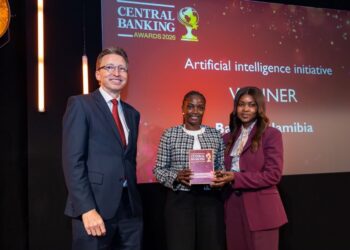Three people on stage at Central Banking Awards 2026; the winner holds a plaque in front of a red backdrop.