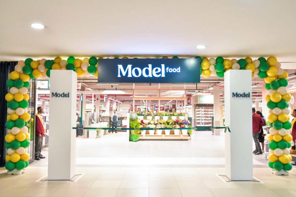 Model store - The Brief | Namibia's Leading Business & Financial News Store entrance with green, yellow, and cream balloon arch and a bold 'Model' sign overhead, welcoming shoppers.