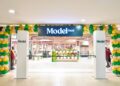 Store entrance with green, yellow, and cream balloon arch and a bold 'Model' sign overhead, welcoming shoppers.