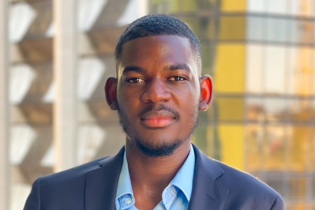ERICK SHAPUMBA - The Brief | Namibia's Leading Business & Financial News Portrait of a young man in a navy blazer and light blue shirt outdoors, facing the camera.