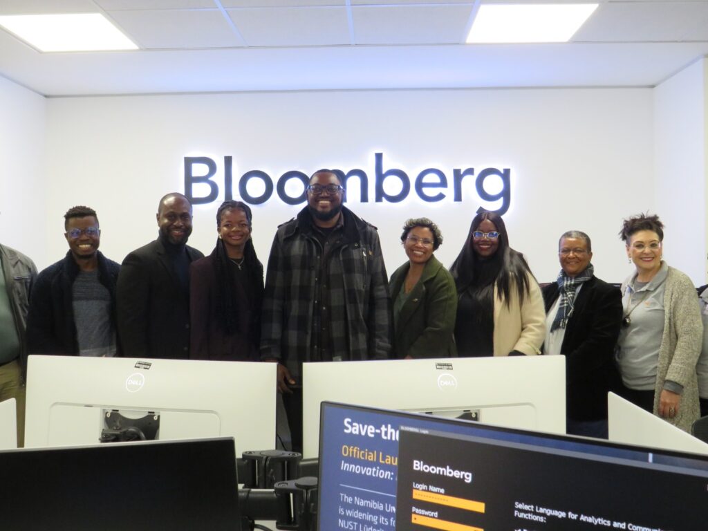 WhatsApp Image 2026-06-18 at 52049 PM - The Brief | Namibia's Leading Business & Financial News Group of coworkers posed in a Bloomberg office, smiling, with desks and computer monitors in the foreground.