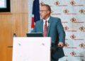 uanguta 7 - The Brief | Namibia's Leading Business & Financial News Man in teal suit delivers a presentation at a white podium with a Namibia Bank of Namibia backdrop