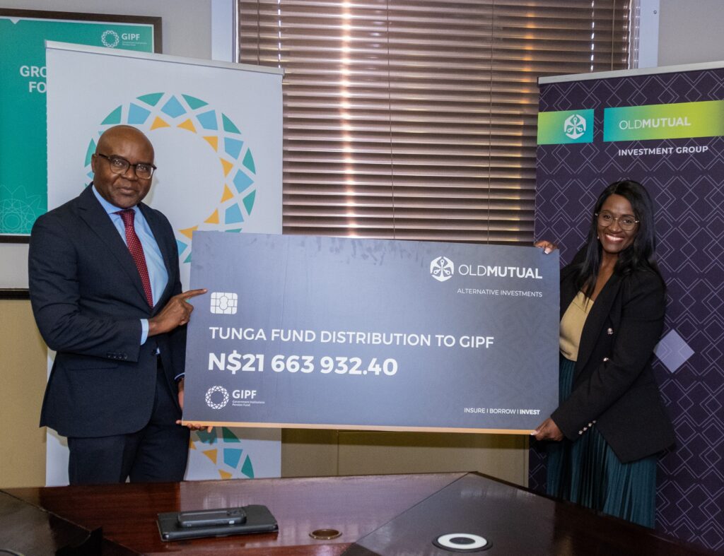 Two professionals hold a large ceremonial check branded Old Mutual, with banners in the background and the amount N,663,932.40 visible.