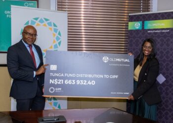 Two professionals hold a large ceremonial check branded Old Mutual, with banners in the background and the amount N$21,663,932.40 visible.