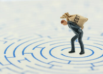 Small figure carrying a burlap sack labeled DEBT walks through a circular maze terming the journey to pay off debt.